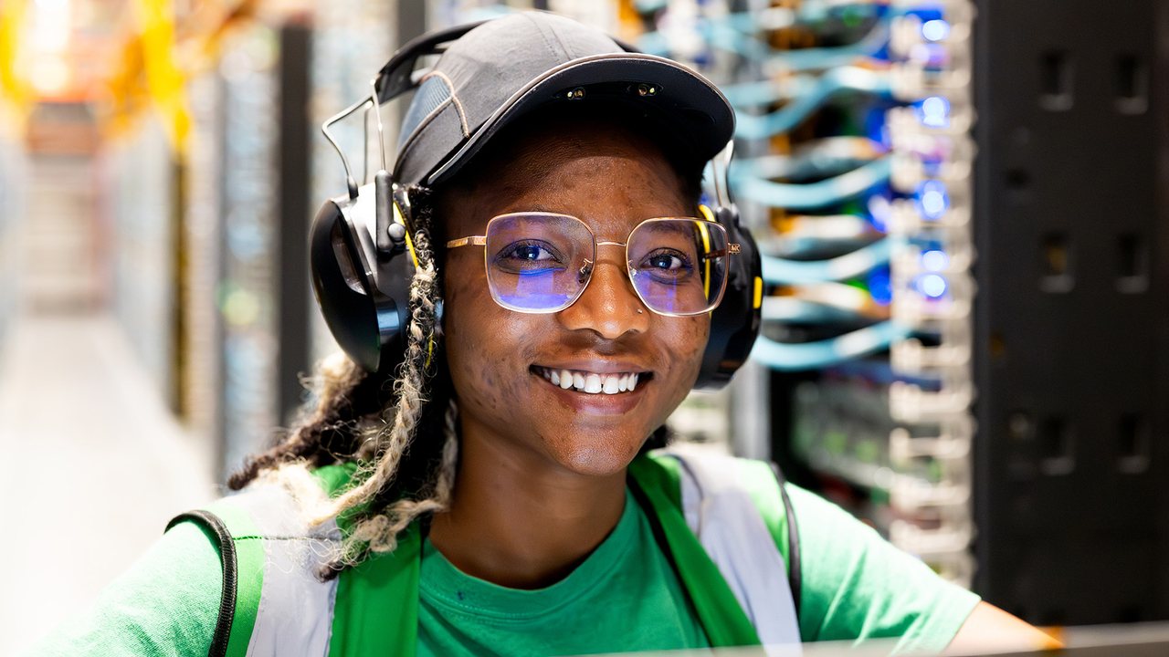 A smiling Markley data center technician in the server hall